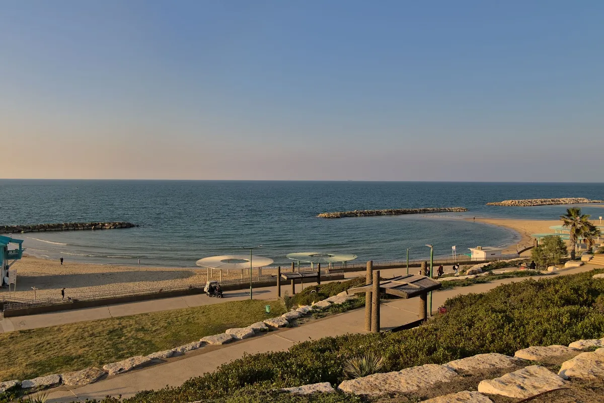 The photo was taken from a higher elevation looking down onto the beach. A path is going town to the sand beach.